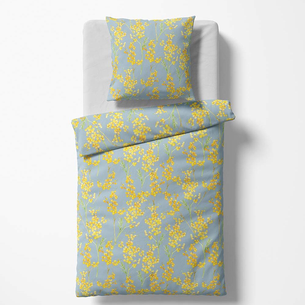 Bettwäsche Blüten fleuresse Ein einzelnes Bett mit weißem Spannbettlaken, auf dem ein Kissen und eine Bettdecke mit einem hellblauen Bezug liegen. Der Bezug ist mit einem floralen Muster aus gelben Blüten und grünen Zweigen bedruckt. Das Muster wiederholt sich gleichmäßig auf Kissen und Decke. Das Bett steht auf einem weißen Hintergrund und ist von oben fotografiert.