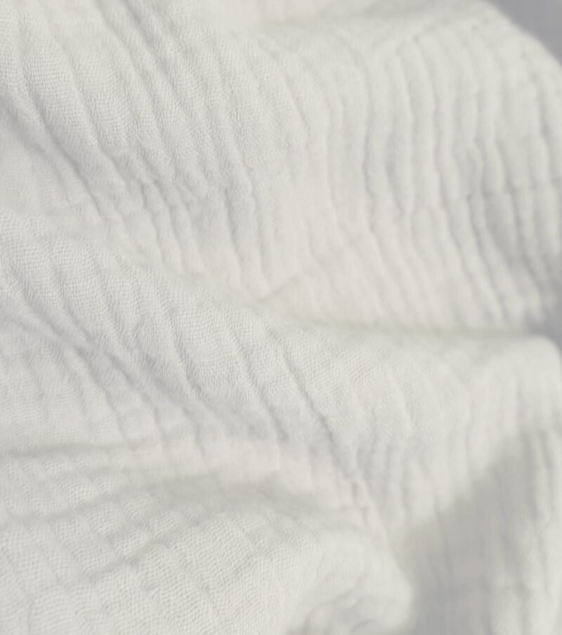 Nahaufnahme von strukturiertem Musselin-Stoff in creme, mit sichtbarer Crinkle-Oberfläche.